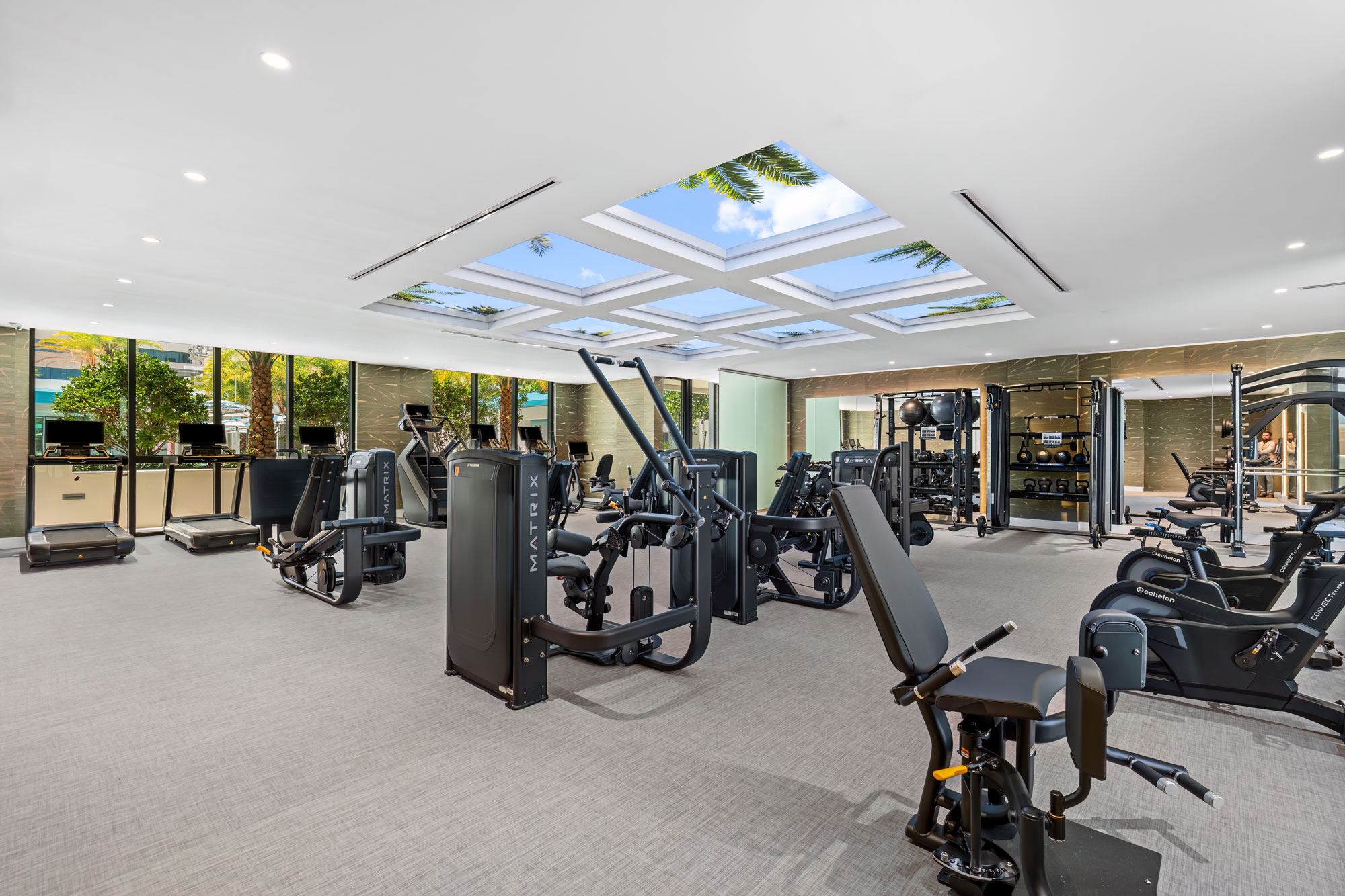 The fitness center: cardio and strength equipment in a double-height room with full-height windows.