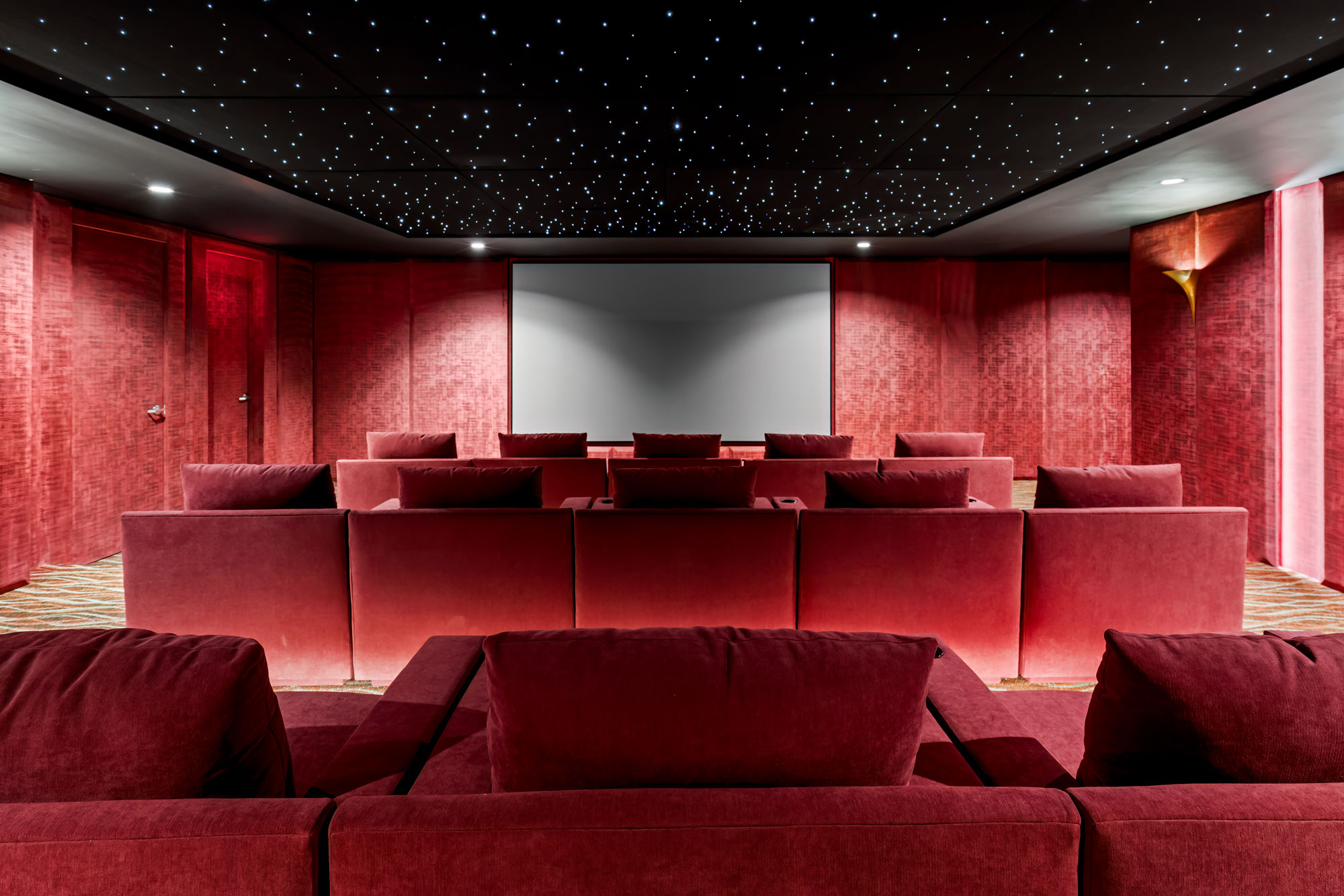 The 15-seat private movie theater: tiered lounge seating facing a large screen.
