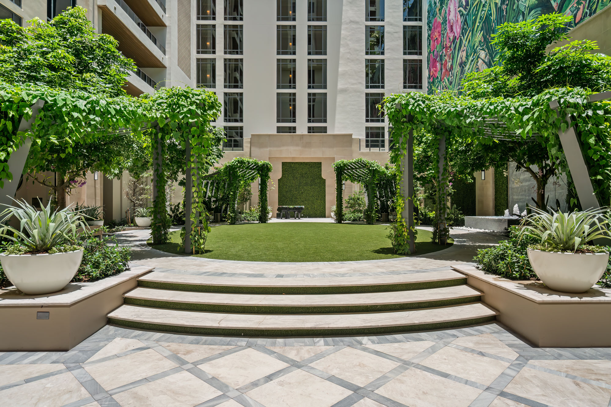 The orchid sanctuary and courtyard: planted beds and seating under a canopy of mature trees.