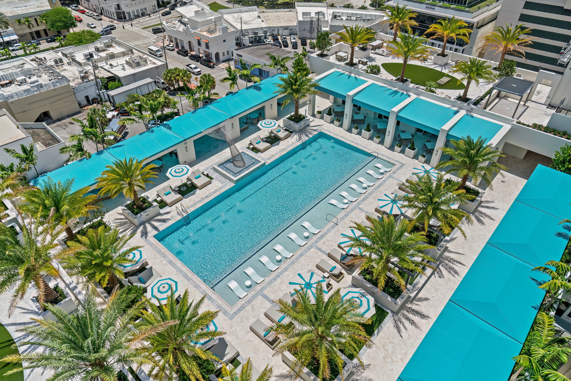 The resort deck at Regency Parc: a long swimming pool bordered by loungers, cabanas and palms, seen from above.